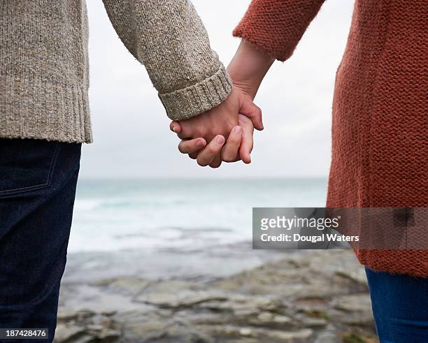 close up of couple holding hands on coastline. - halb mann halb frau stock-fotos und bilder