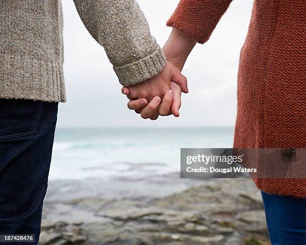 close up of couple holding hands on coastline. - de mãos dadas imagens e fotografias de stock