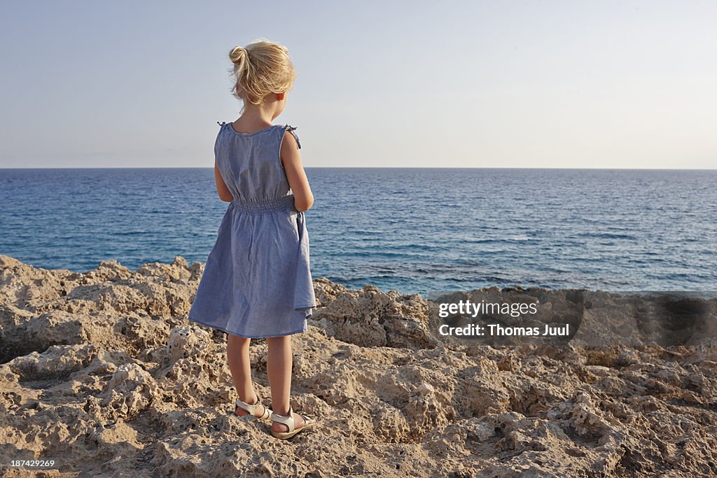 Girl standing on rocks and looking over the sea