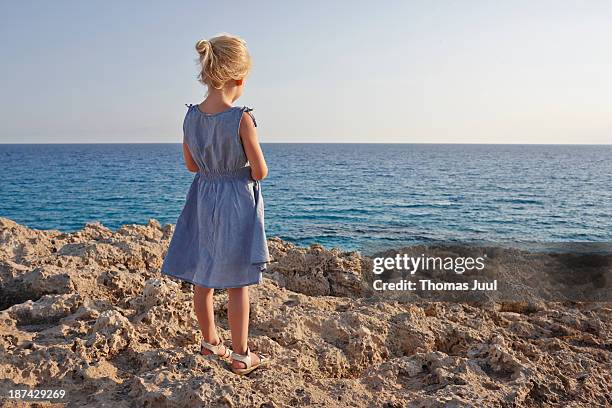 girl standing on rocks and looking over the sea - kids standing stock-fotos und bilder