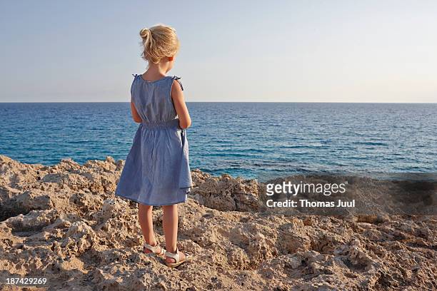 girl standing on rocks and looking over the sea - vista posteriore foto e immagini stock