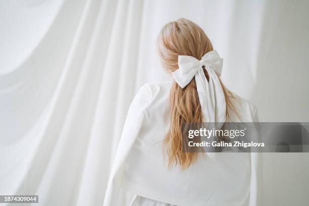 young woman with long blonde hair and white bow in evening dress on white background - haarschmuck stock-fotos und bilder