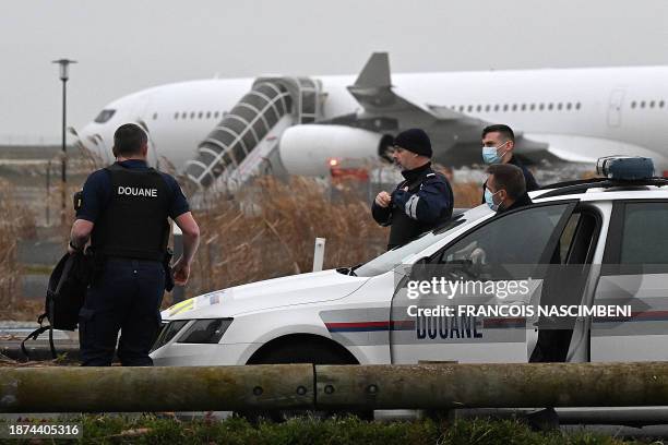 French customs officers stand next to a customs car with an Airbus A340 in the background which was grounded on the tarmac since December 21 over...