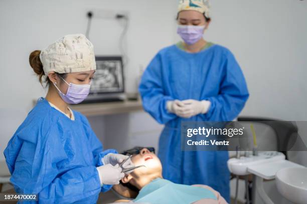 female dentist in face mask and glasses doing treatment - plaque remover stock pictures, royalty-free photos & images