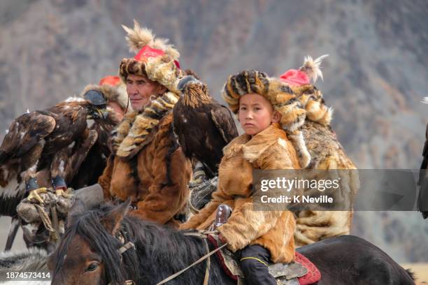 kazakh eagle hunter and a young boy at the sagsai eagle festival - itinerant stock pictures, royalty-free photos & images