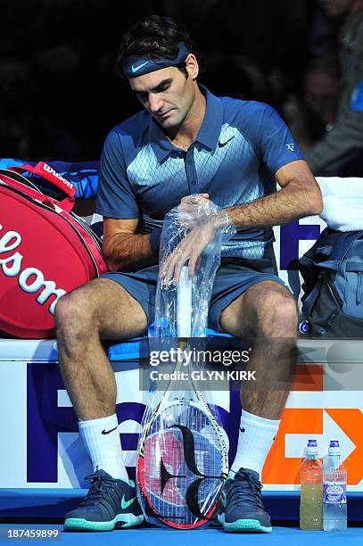 Switzerland's Roger Federer takes a fresh racquet in a break between games against Argentina's Juan Martin Del Potro during their group B singles...