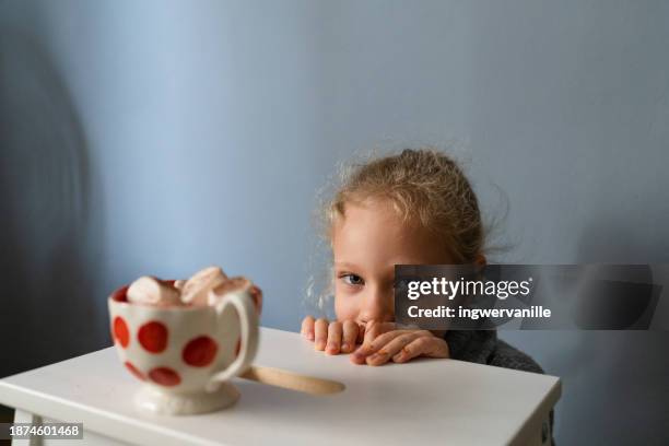 cute girl peeking over the table with  hot chocolate - marshmallow peeps ストックフォトと画像