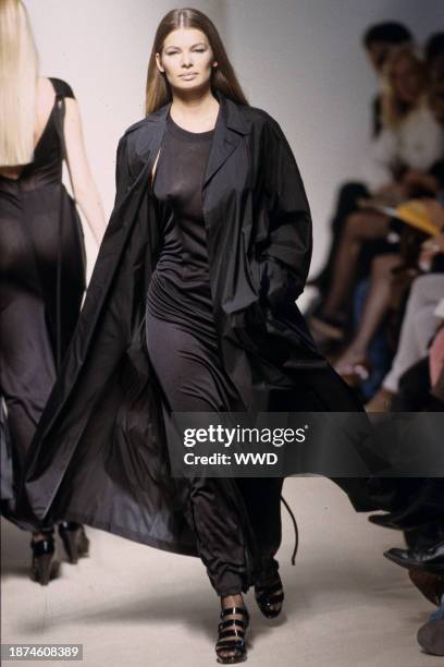 Model wears a sheer black sleeveless blouse and ankle-length skirt under a thin black jacket, all by Jil Sander