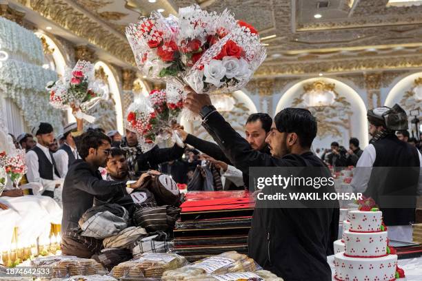 Afghan volunteers distribute flower bouquets to the grooms during a mass wedding ceremony at a wedding hall in Kabul on December 25, 2023. Fifty...