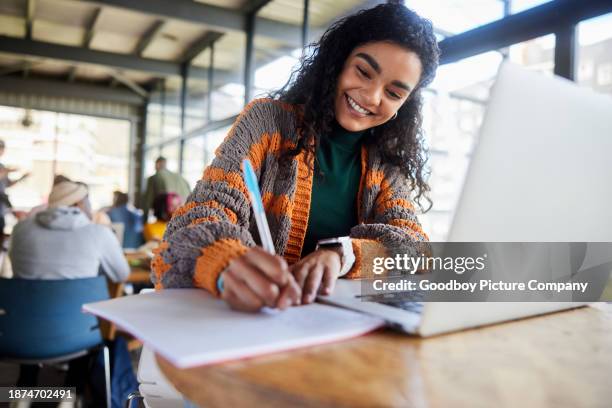 young female college student smiling while doing homework in a school cafeteria - women on laptop stock pictures, royalty-free photos & images