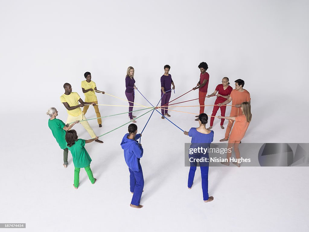 Group of people pulling connected color ropes