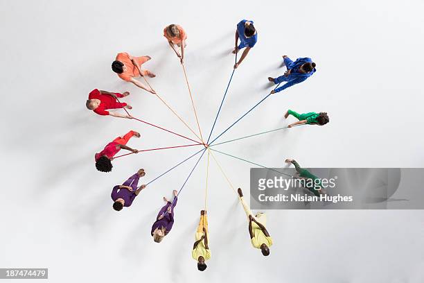 circle of people pulling on connected ropes - cooperazione foto e immagini stock