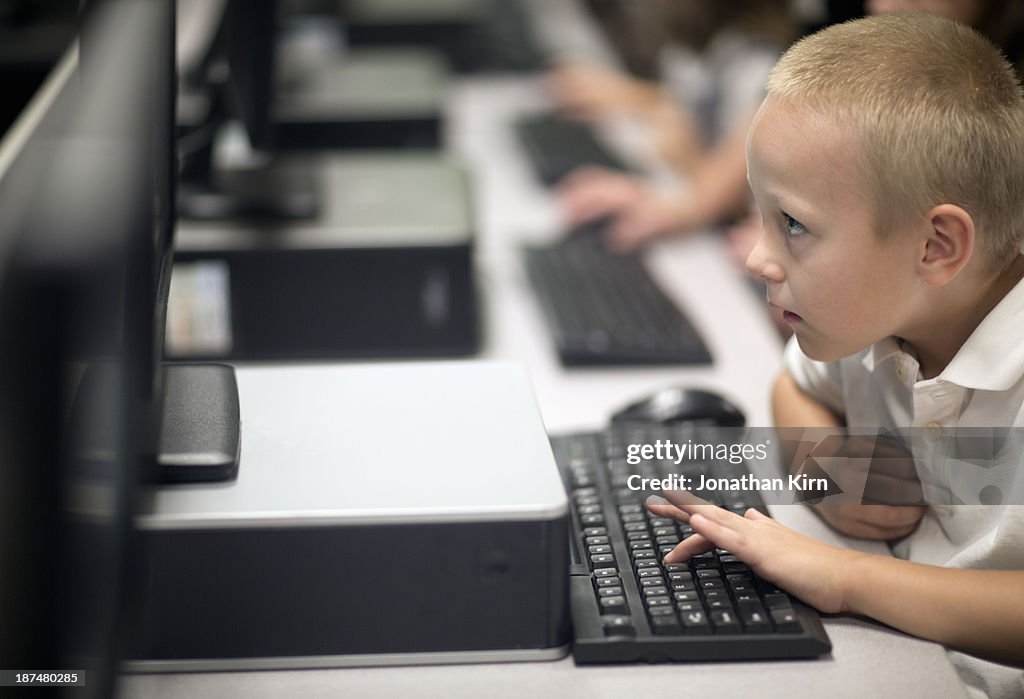 First grade school children learn on computers.