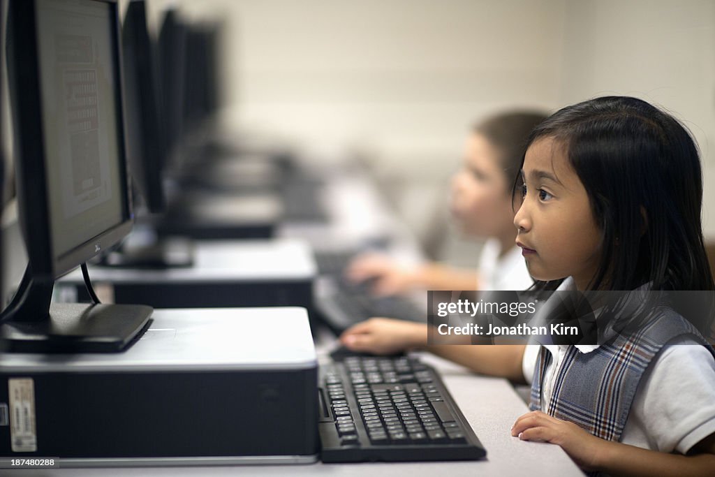 First grade school children learn on computers.