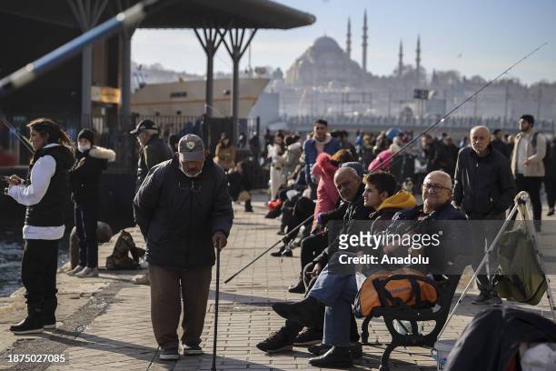 People are fishing and walking by the shore during sunny weather at Eminonu district of Istanbul, Turkiye on December 25, 2023.