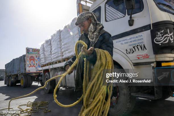 An Egyptian truck driver coils a rope over used for covering a tarp while humanitarian aid is inspected after before entering Gaza at the Kerem...