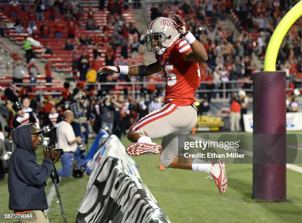 Tim Cornett of the UNLV Rebels leaps over a sideline advertising sign behind the end zone after scoring on a four-yard touchdown run against the Utah...