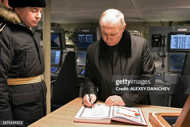 In this pool photograph distributed by Russian state agency Sputnik, Russia's President Vladimir Putin leaves an entry in the guestbook following a...