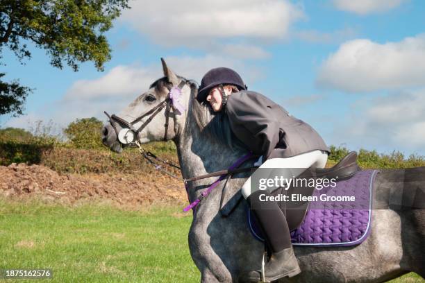 pretty young female rider hugs her beautiful grey horse after competing in an event in an agricultural show in rural england uk - placecompetes stock pictures, royalty-free photos & images