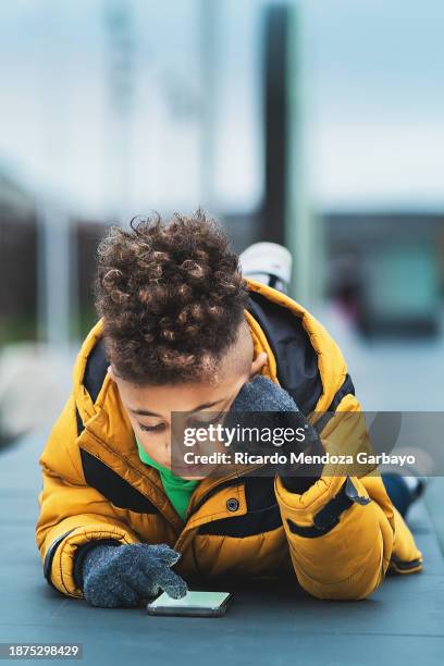 small ecuadorian boy in a yellow jacket exploring the urban environment - afro caribbean portrait stock pictures, royalty-free photos & images