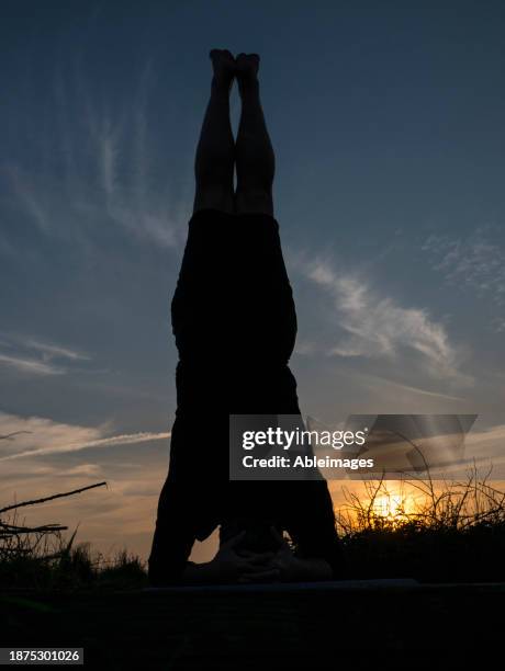 man practicing yoga outdoors at sunset, headstand pose - shirshasana stock pictures, royalty-free photos & images