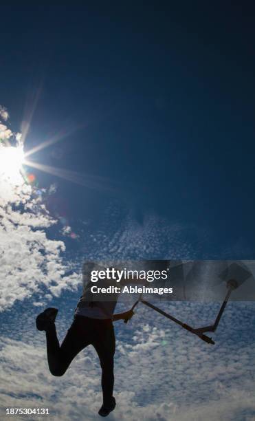 skateboarder jumping mid air against clouds and blue sky - extreme sports kids stock pictures, royalty-free photos & images