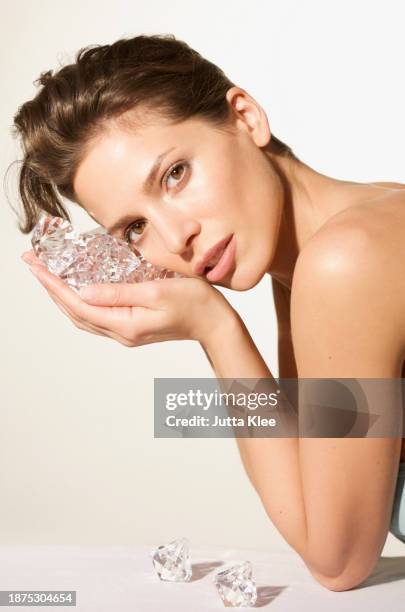 young woman holding large diamonds next to her face - glitter face stock pictures, royalty-free photos & images