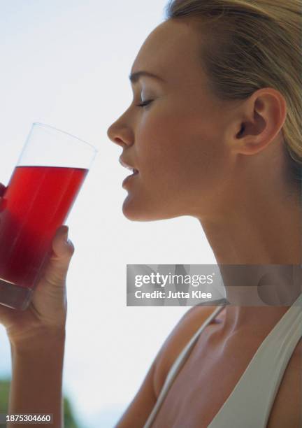 close up profile of a woman drinking cranberry juice - cranberry juice stock pictures, royalty-free photos & images