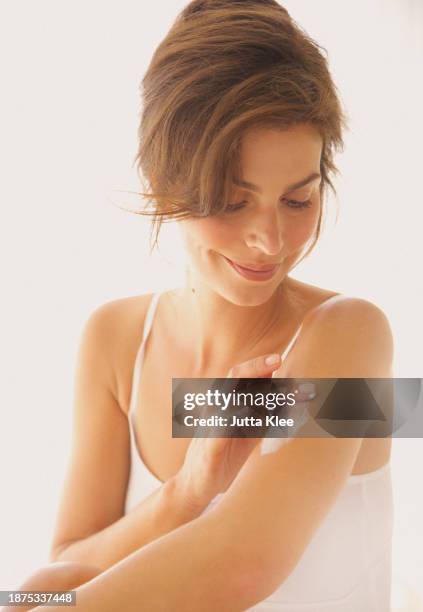 woman applying body lotion on arm - crema corporal fotografías e imágenes de stock