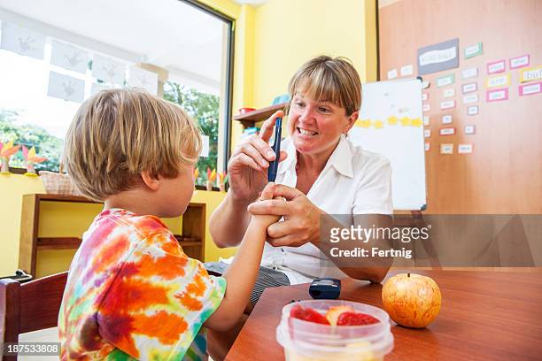 testing blood sugar at school - moving image stock pictures, royalty-free photos & images
