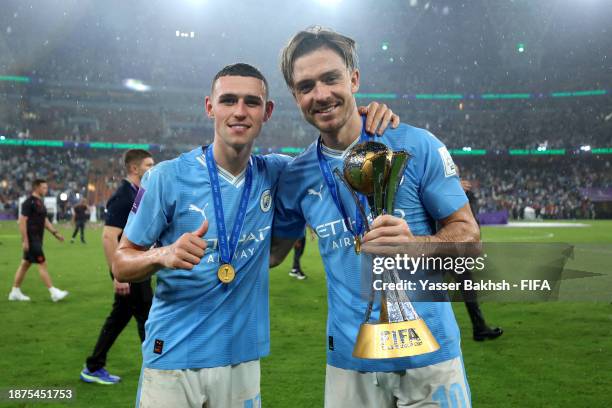 Phil Foden and Jack Grealish of Manchester City pose for a photograph with the FIFA Club World Cup trophy after their team's victory in the FIFA Club...