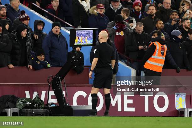 Match Referee Anthony Taylor checks the Video Assistant Referee screen before disallowing the first goal scored by Leon Bailey of Aston Villa during...