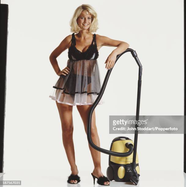 Swedish television presenter Ulrika Jonsson poses with a vacuum cleaner, 1996.