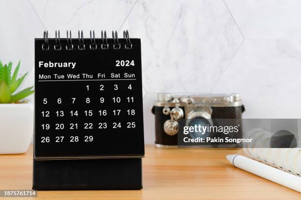 desk calendar 2024: february calendar is used to plan daily work and life with houseplant and camera on the work table. - febrero fotografías e imágenes de stock