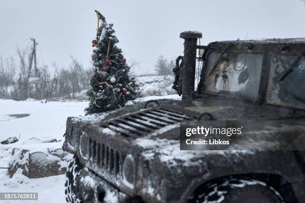 Ukrainian soldiers passing by in a HMMWV stop to take a photo of a Christmas tree at a destroyed checkpoint on a road which is constantly under fire...