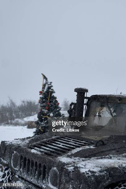 Ukrainian soldiers passing by in a HMMWV stop to take a photo of a Christmas tree at a destroyed checkpoint on a road which is constantly under fire...
