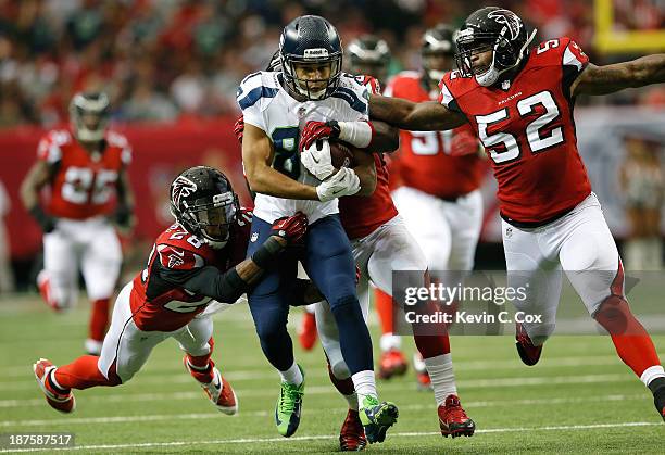 Golden Tate of the Seattle Seahawks drags Thomas DeCoud, Joplo Bartu and Akeem Dent of the Atlanta Falcons after a reception at Georgia Dome on...