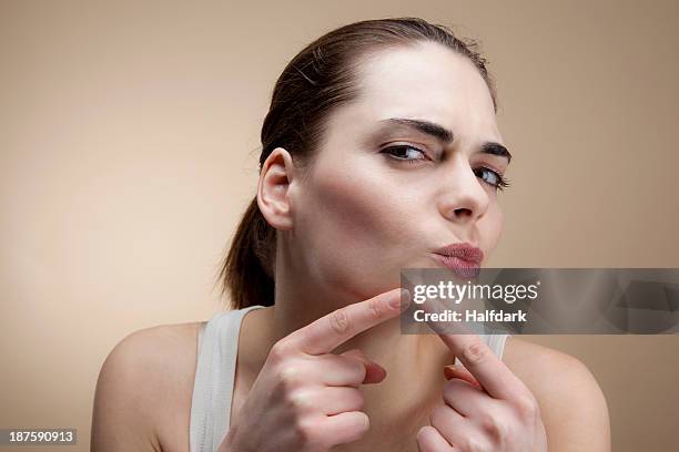 a young woman concentrating as she squeezes a pimple - kin stockfoto's en -beelden