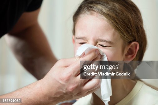 Father wiping daughter's nose with tissue Father wiping daughter's nose with tissue