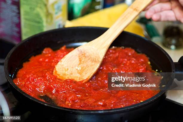 tomato sauce in frying pan with wooden spatula - tomatensoße stock-fotos und bilder