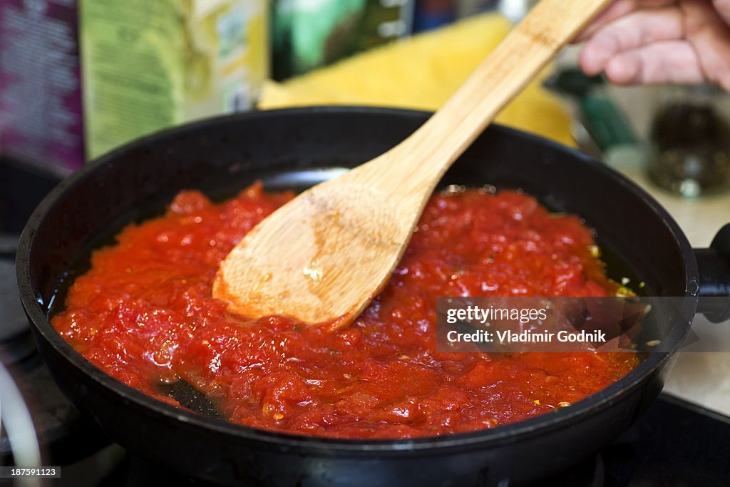 Tomato sauce in frying pan with wooden spatula