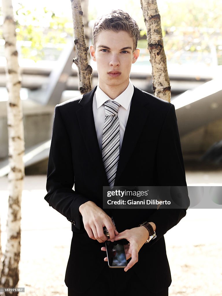 A young businessman holding a smart phone and looking serious