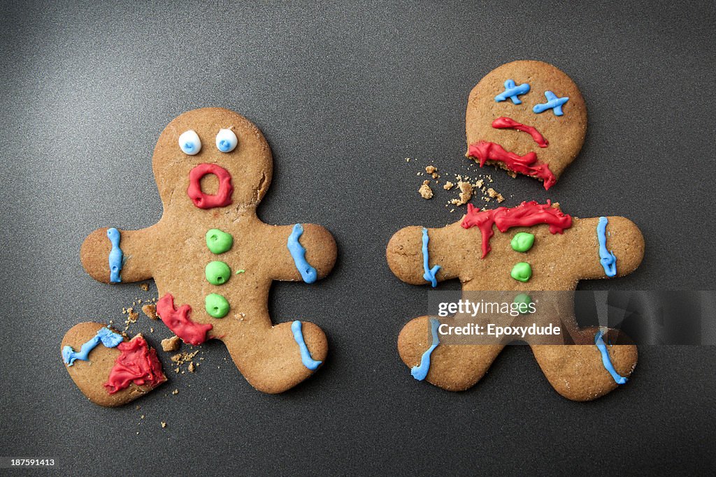 A shocked gingerbread man with broken leg next to a decapitated gingerbread man