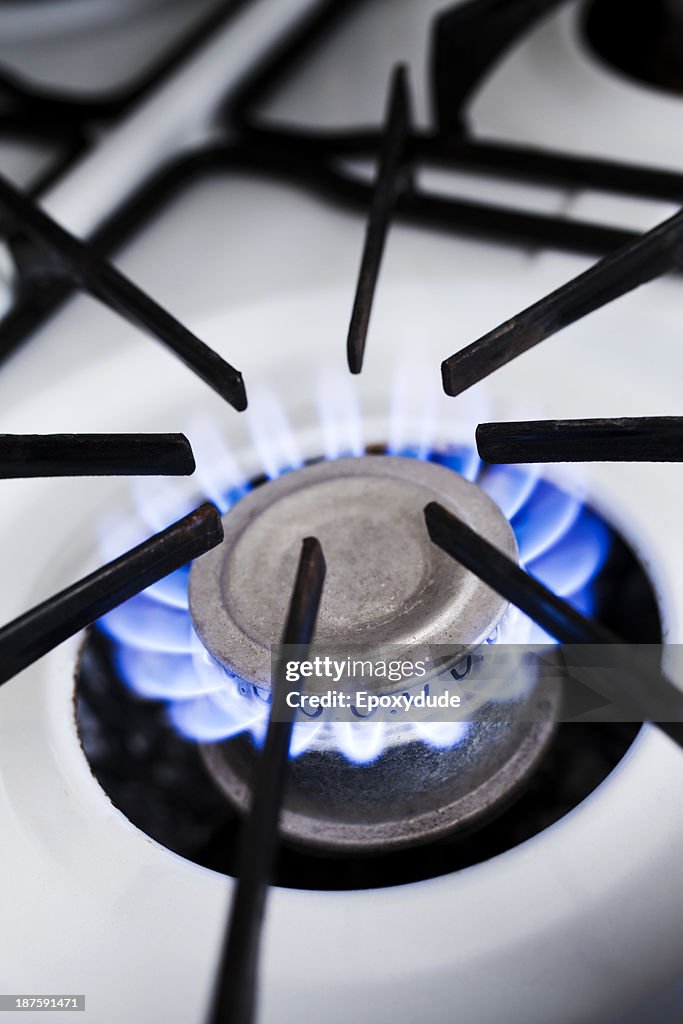 The blue flame of a lit gas stove burner, close-up