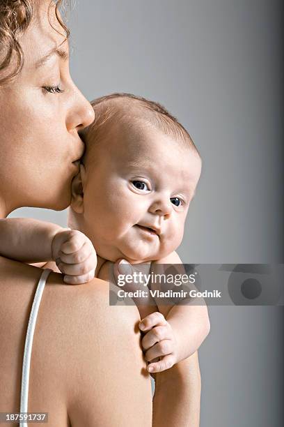 mother kissing her child on the head - baby studio shot stock pictures, royalty-free photos & images