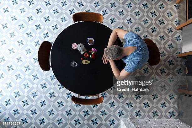 a man sitting at a table with his head resting on his arms, directly above - head on table stock-fotos und bilder