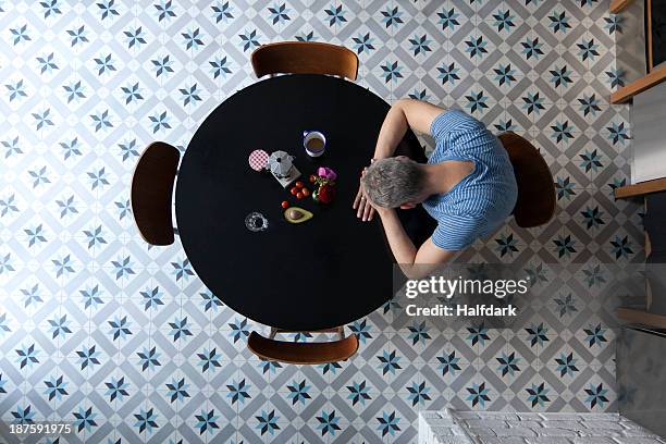 a man sitting at a table with his head resting on his arms, directly above - man with head on table photos et images de collection