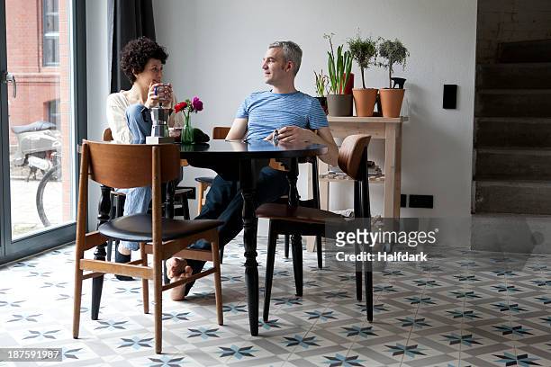 a cheerful hip mixed age couple enjoying breakfast together in their dining room - routine bildbanksfoton och bilder
