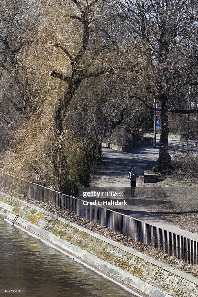 A young man jogging through a city park