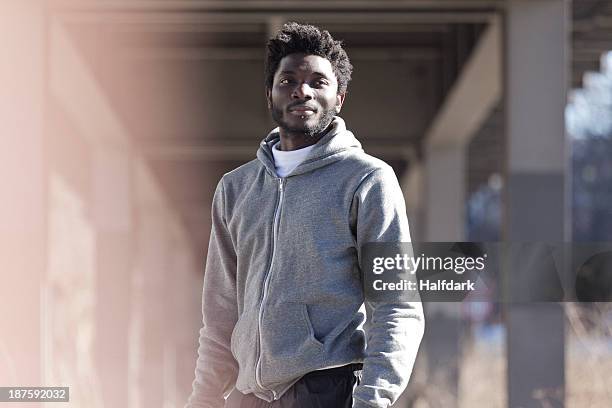 a hip young man standing in sports gear under a city bridge - chin piercing stock pictures, royalty-free photos & images